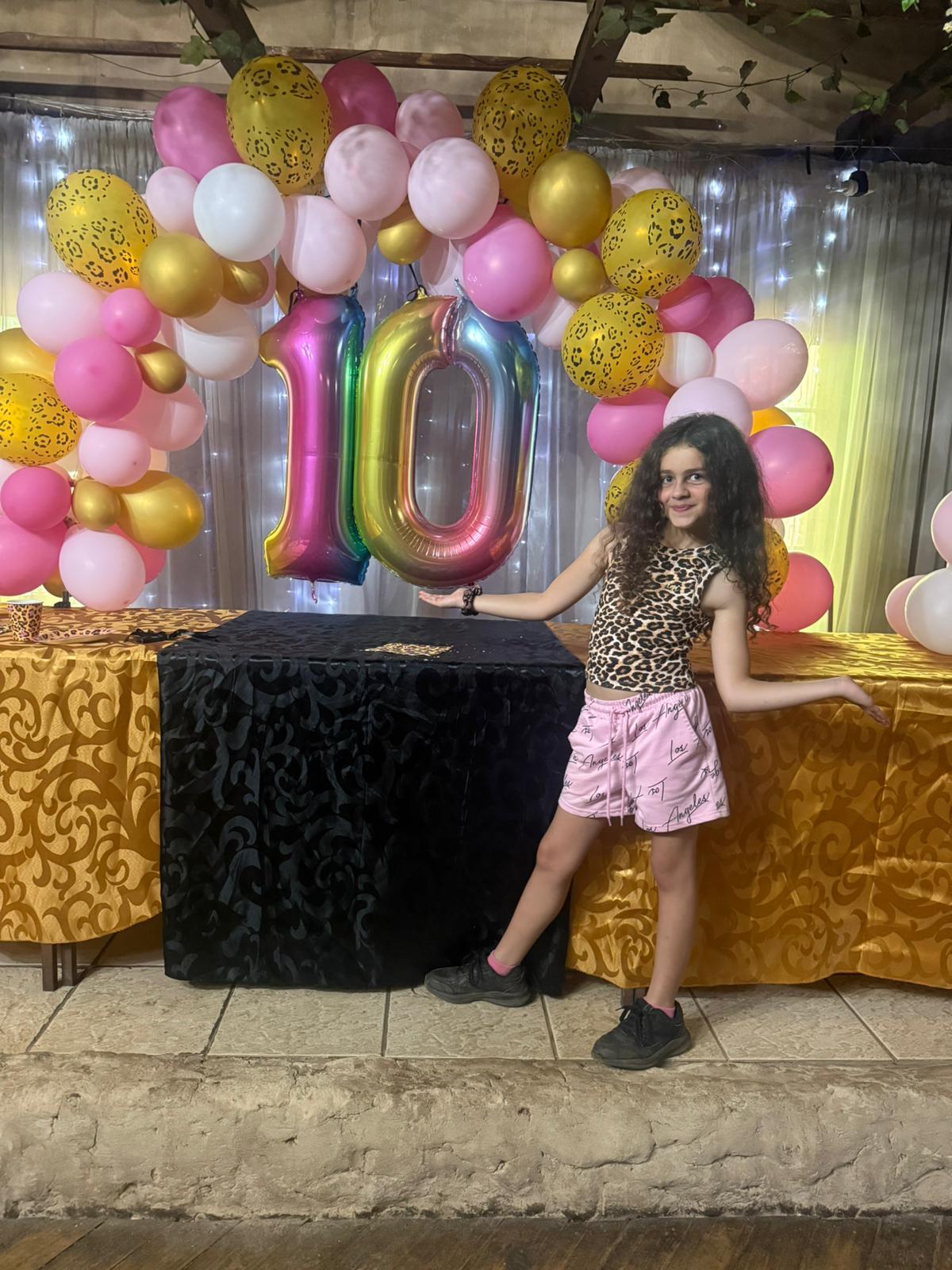 Birthday girl posing with balloon arch